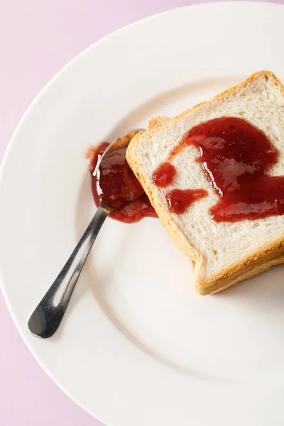 Close up view of toasts and spoon with jam on white plate isolated on violet — Stock Photo