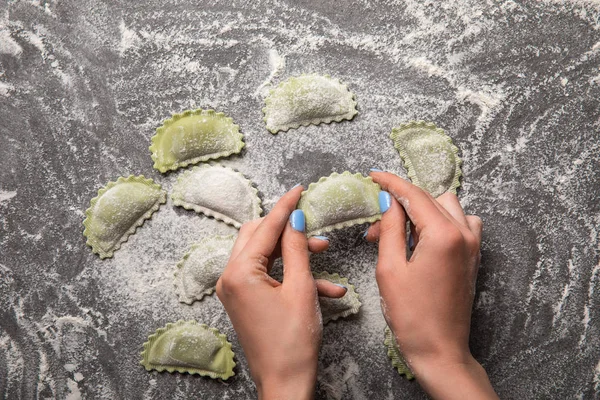 Vista ritagliata della donna che tiene i ravioli verdi con farina — Foto stock