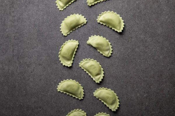 Vue de dessus des raviolis verts bruts sur la surface texturée grise — Photo de stock