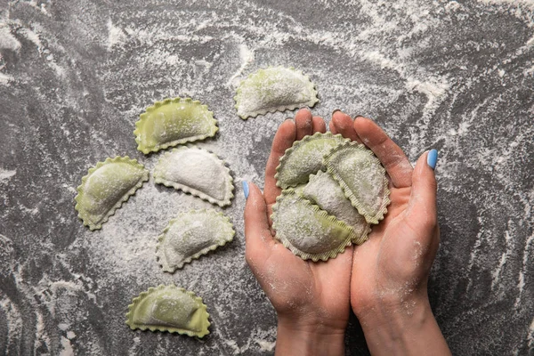 Vista cortada de mulher segurando ravioli verde cru em mãos — Fotografia de Stock