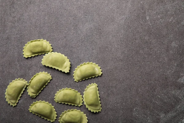 Top view of green raw ravioli on grey textured surface with copy space — Stock Photo