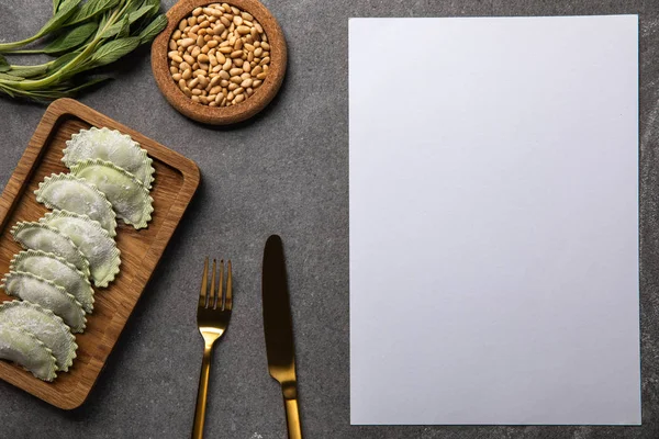 Servido em tábua de madeira ravioli verde com farinha perto de tigela com sementes, ervas, talheres e cartão em branco — Fotografia de Stock