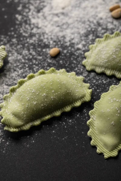 Close up view of green ravioli with flour on black table — Stock Photo