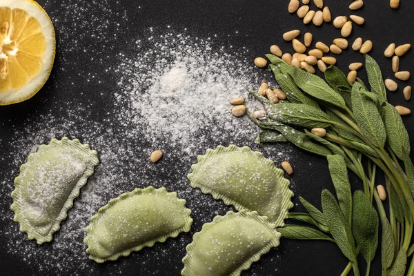 Top view of raw green ravioli with pine nuts, flour, green sage and lemon — Stock Photo