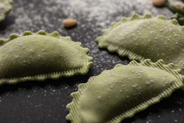 Close up vista de ravioli verde cru com farinha na mesa preta — Fotografia de Stock