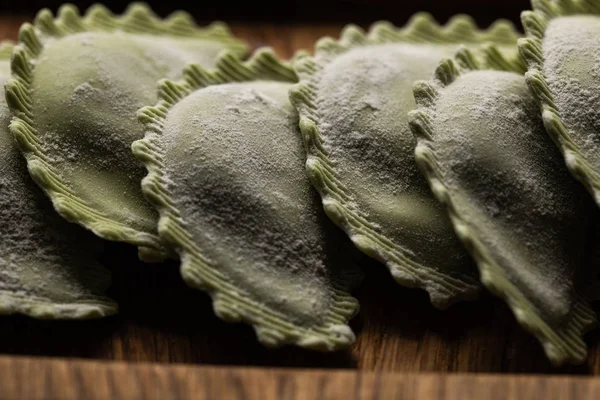 Close up view of raw green ravioli on wooden board — Stock Photo