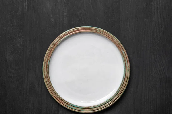 Vista superior da placa redonda vazia branca vintage na mesa de madeira preta — Fotografia de Stock