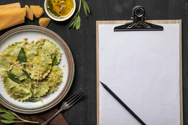 Draufsicht auf servierte Ravioli und leere weiße Menüvorlage mit Bleistift — Stockfoto