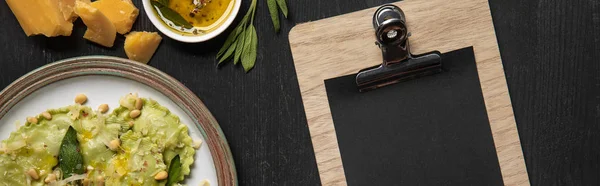 Top view of served ravioli and empty black menu template, panoramic shot — Stock Photo