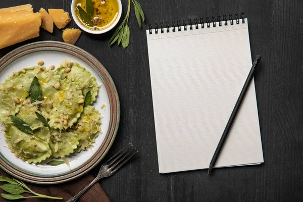 Vue du dessus des raviolis servis et cahier blanc vide avec crayon — Photo de stock