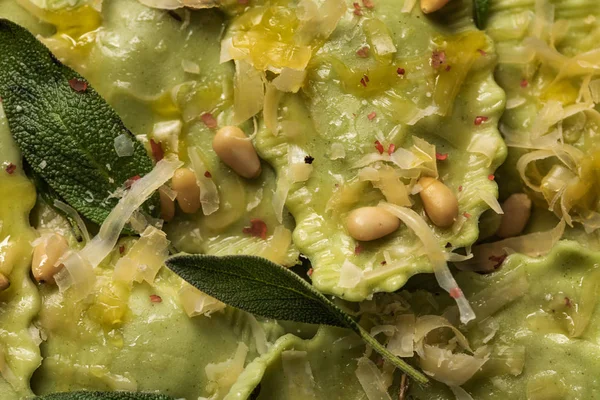 Nahaufnahme von grünen Ravioli mit geschmolzenem Käse, Pinienkernen und grünen Salbeiblättern — Stock Photo