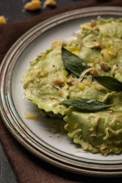 Vista de perto de ravioli verde com queijo derretido, pinhões e folhas de sálvia verde em placa retro — Fotografia de Stock