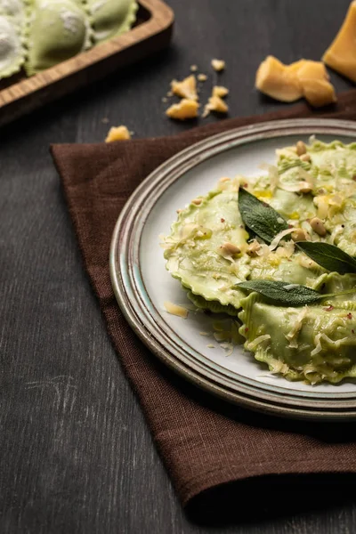 Vista de perto de ravioli verde com queijo derretido, pinhões e folhas de sálvia verde em placa retro — Fotografia de Stock