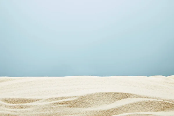 Arena dorada con textura ondulada sobre fondo azul - foto de stock