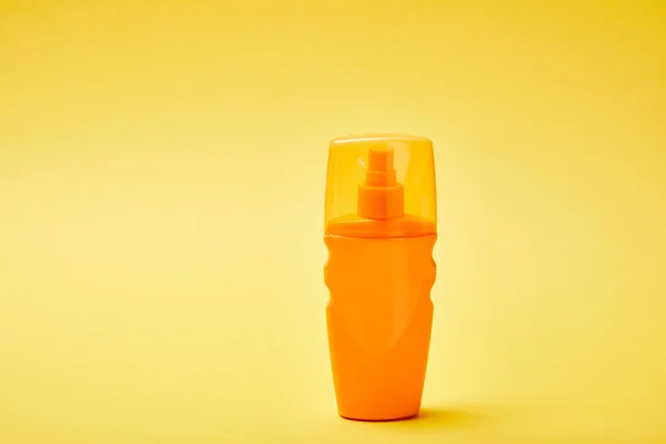 Sonnencreme in orangefarbener Flasche auf gelbem Hintergrund — Stockfoto