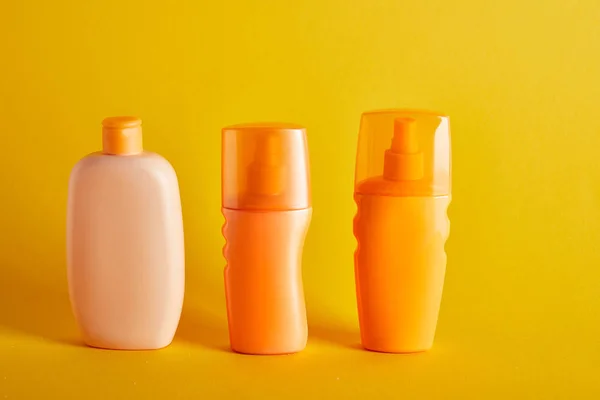 Cosmétiques bronzage en bouteilles sur fond jaune foncé — Photo de stock