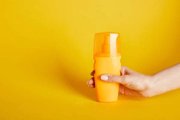 Abgeschnittene Ansicht einer Frau mit Sonnencreme in der Flasche auf gelbem Hintergrund — Stockfoto