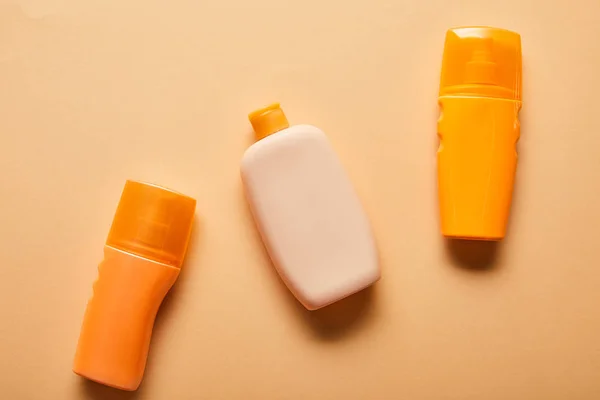 Vista superior de los productos de protección solar en botellas sobre fondo beige - foto de stock