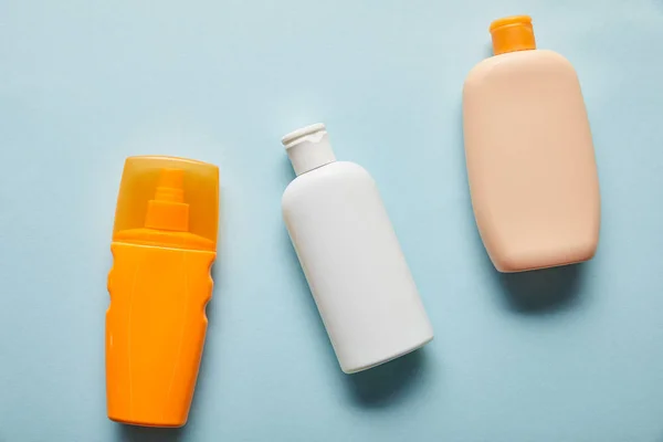 Ansicht von Sonnenschutzmitteln in Flaschen auf blauem Hintergrund — Stockfoto