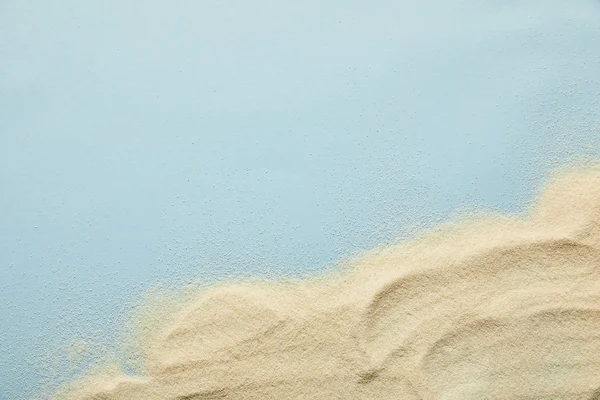 Vista superior de areia dourada ondulada texturizada no fundo azul com espaço de cópia — Fotografia de Stock