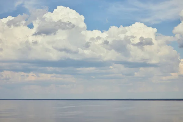 Пейзаж с рекой и белыми облаками на голубом небе — стоковое фото