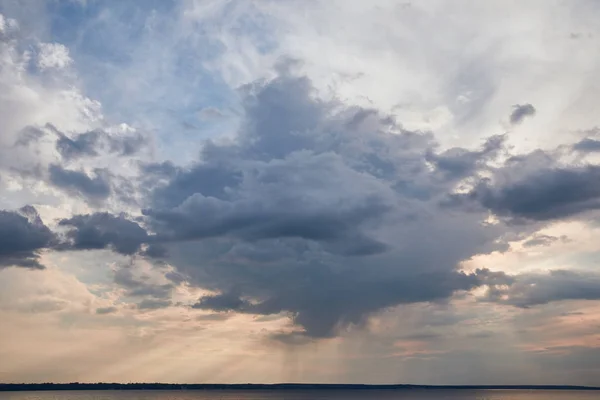 Nuvem escura e raios de sol no fundo azul céu — Fotografia de Stock