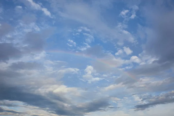 Vista del arco iris sobre fondo cielo azul y nubes azules - foto de stock