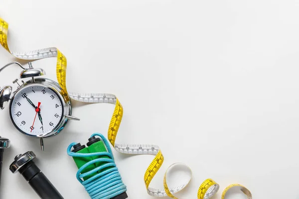 Top view of sport equipment, measuring tape, alarm clock on white background — Stock Photo