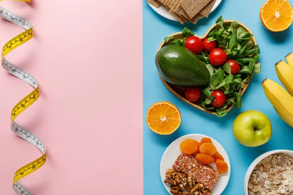 Vista dall'alto del cibo dieta su nastro blu e misurazione su sfondo rosa — Foto stock