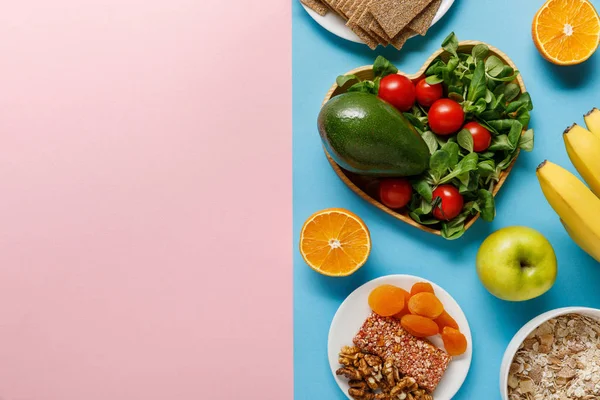 Vista superior de los alimentos dietéticos sobre fondo azul y rosa con espacio para copiar - foto de stock