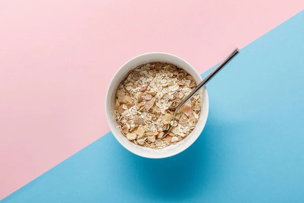 Vista superior de los cereales de desayuno en tazón sobre fondo azul y rosa - foto de stock