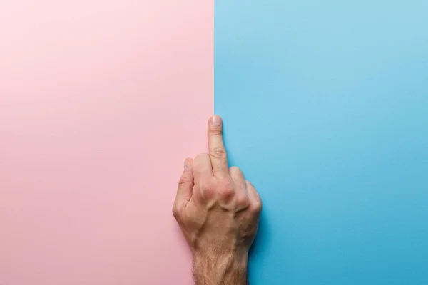 Vista recortada del hombre mostrando el dedo medio sobre fondo rosa y azul - foto de stock