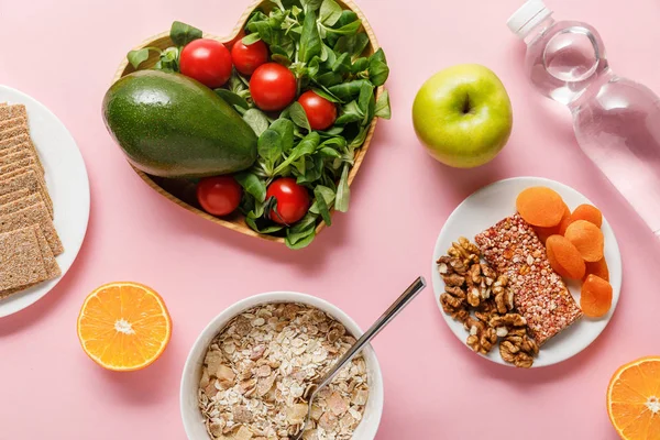 Vista dall'alto di alimenti dietetici freschi e acqua su sfondo rosa — Foto stock