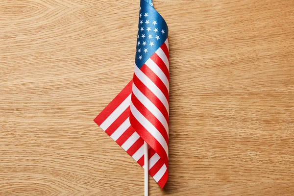 Vista superior de la bandera americana en palo sobre superficie de madera - foto de stock