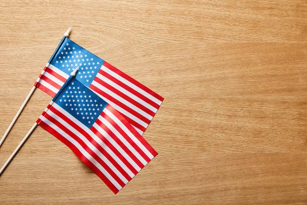 Vue de dessus des drapeaux américains sur les bâtons sur la surface en bois avec espace de copie — Photo de stock