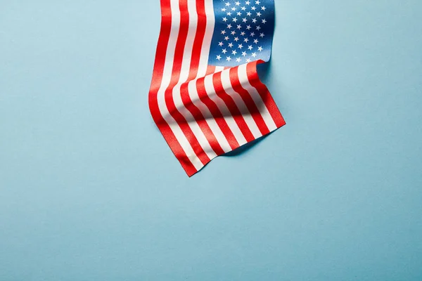 Vista superior de la bandera americana en palo sobre fondo azul con espacio de copia - foto de stock
