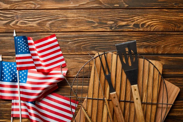 Вид на американские флаги рядом с оборудованием для барбекю на деревянном деревенском столе — стоковое фото