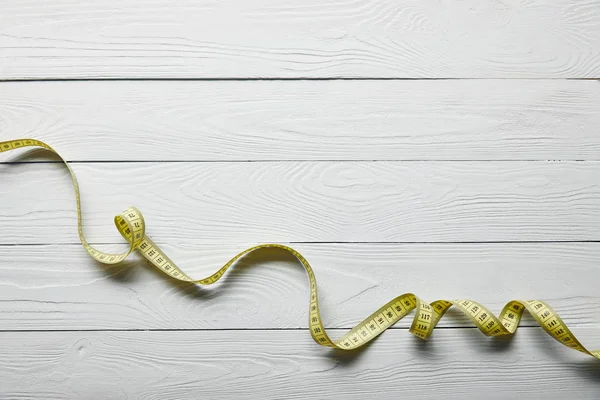 Gelbes Maßband auf weißem Holzgrund mit Kopierraum — Stockfoto