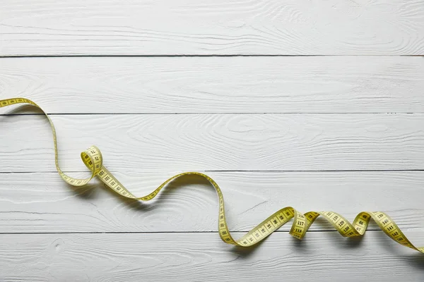 Top view yellow measuring tape on wooden white background with copy space — Stock Photo