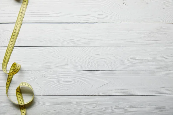 Ruban à mesurer jaune sur surface blanche en bois avec espace de copie — Photo de stock