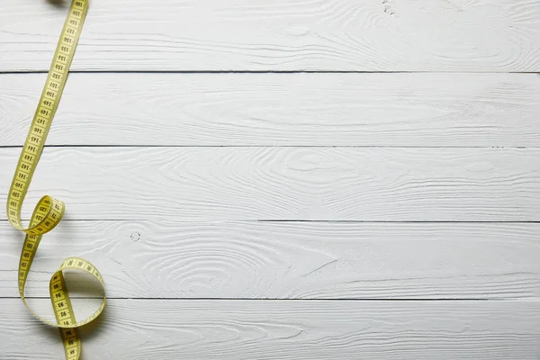 Top view yellow measuring tape on wooden white surface with copy space — Stock Photo