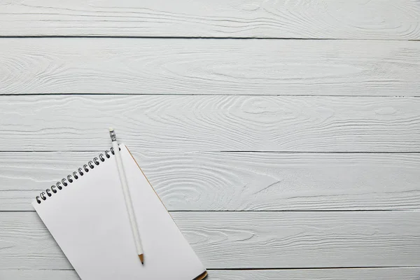 Top view of blank notebook with pencil on wooden white background with copy space — Stock Photo