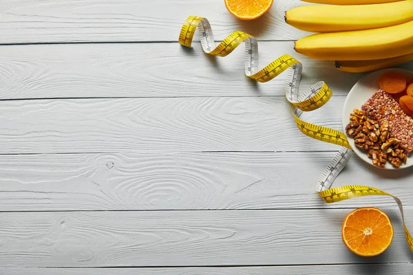 Vista dall'alto di frutta fresca, metro a nastro e dadi su fondo bianco in legno con spazio copia — Foto stock