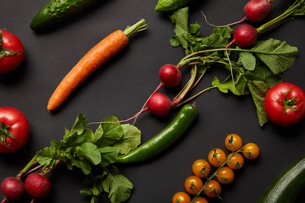 Légumes savoureux nutritifs crus avec des feuilles vertes sur fond noir — Photo de stock