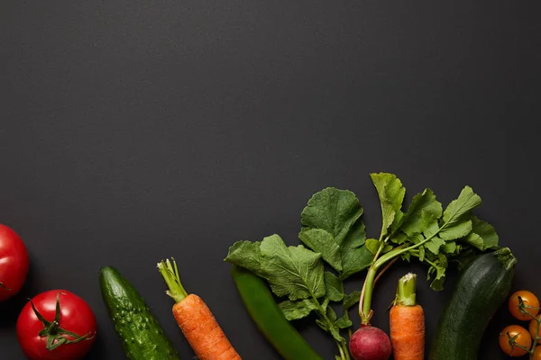 Vista superior de vegetais saborosos nutritivos crus com folhas verdes no fundo preto com espaço de cópia — Fotografia de Stock