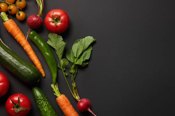 Top view of raw tasty vegetables with green leaves on black background with copy space — Stock Photo