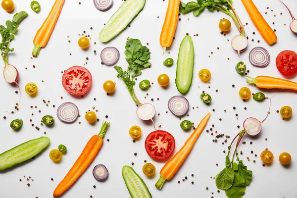 Vista superior de verduras en rodajas y pimienta negra sobre fondo blanco - foto de stock