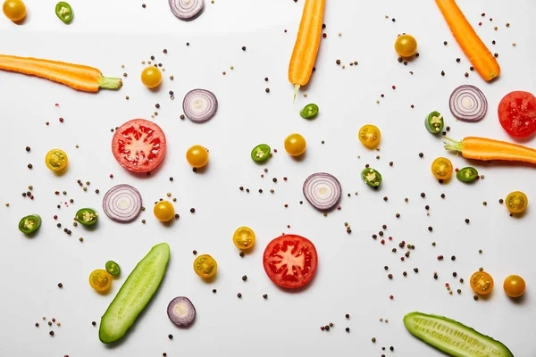 Вид сверху на органические нарезанные овощи и черный перец на белом фоне — стоковое фото