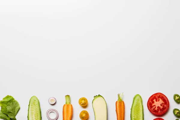 Tendido plano con verduras orgánicas en rodajas sobre fondo blanco con espacio de copia - foto de stock