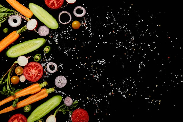 Vue de dessus des tranches de légumes frais avec sel isolé sur noir avec espace de copie — Photo de stock